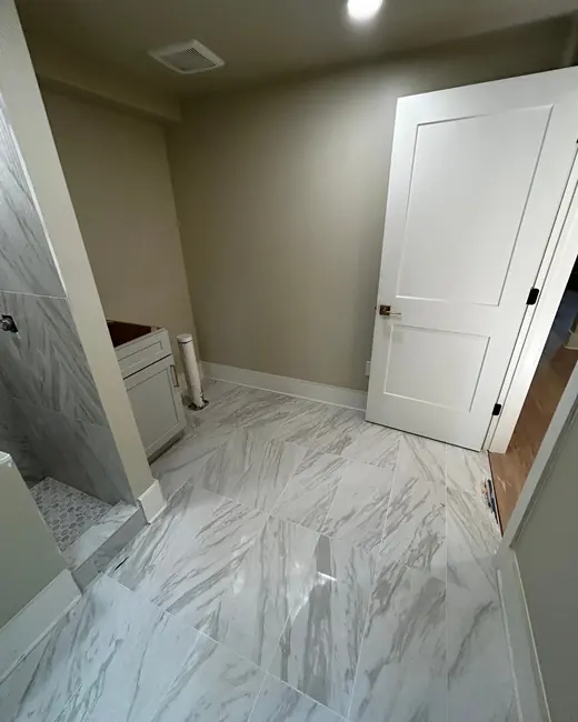 Marble tile floor and white panel door in a newly finished bathroom hallway