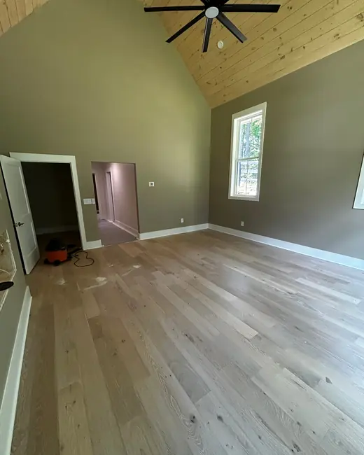 Room with a vaulted wood plank ceiling and clean wide-plank floors