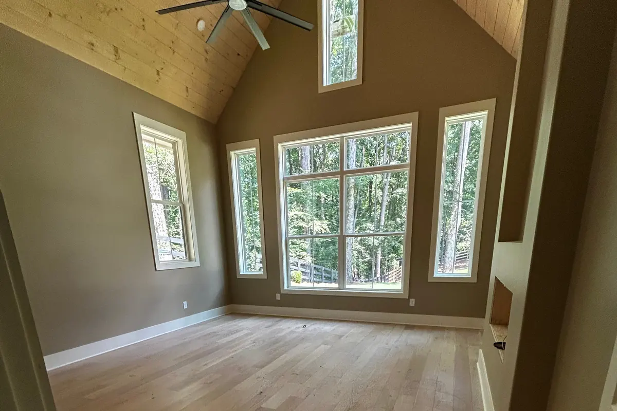 Vaulted great room in a new build with a wood plank ceiling, tall windows and clean wide-plank floors